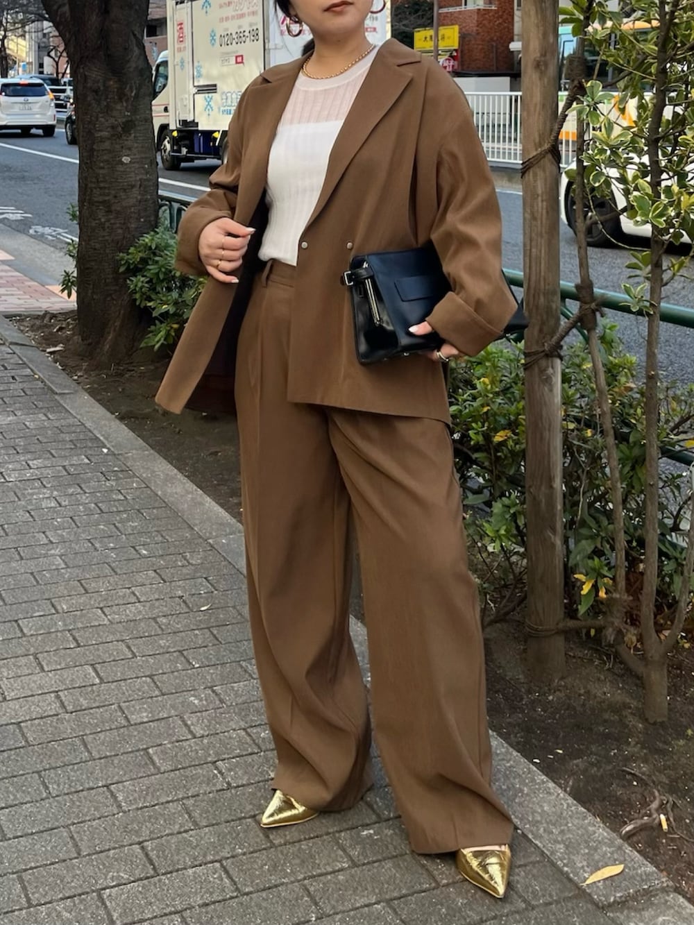 ブラウン系のテーラードジャケット、ブラウン系のその他パンツ、ゴールド系のサンダルを着用したレディースの冬コーディネートの2枚目の写真