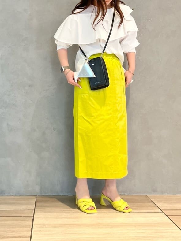 イエロー系のスカート、ホワイト系のシャツ/ブラウス、イエロー系のサンダルを着用したレディースの春コーディネートの2枚目の写真
