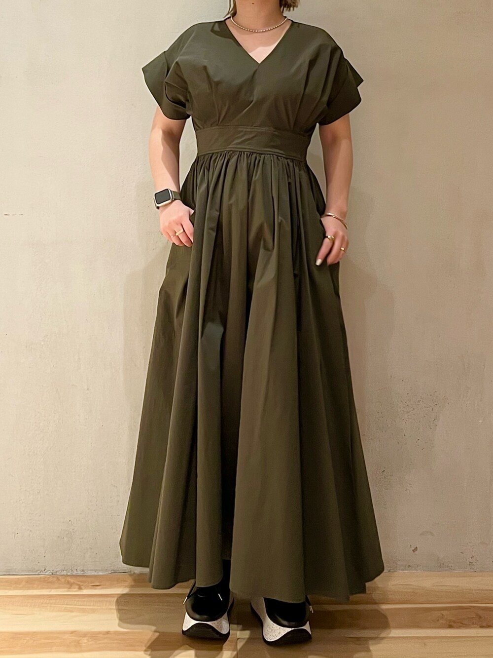 グリーン系のワンピース、ブラック系のスニーカー、シルバー系のネックレスを着用したレディースの冬コーディネートの4枚目の写真