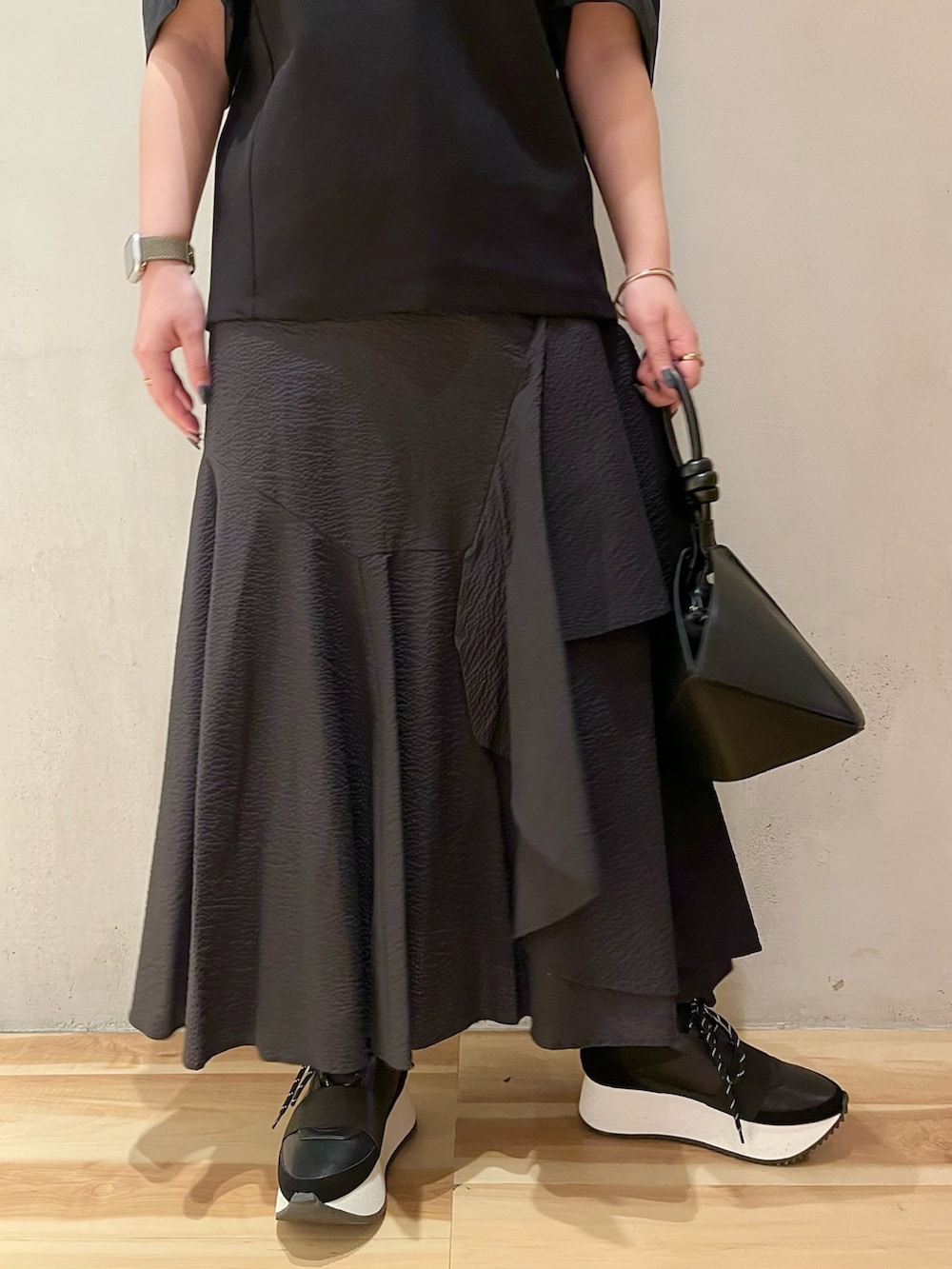 ブラック系のTシャツ/カットソー、ブラック系のスカート、ブラック系のハンドバッグを着用したレディースの春コーディネートの6枚目の写真