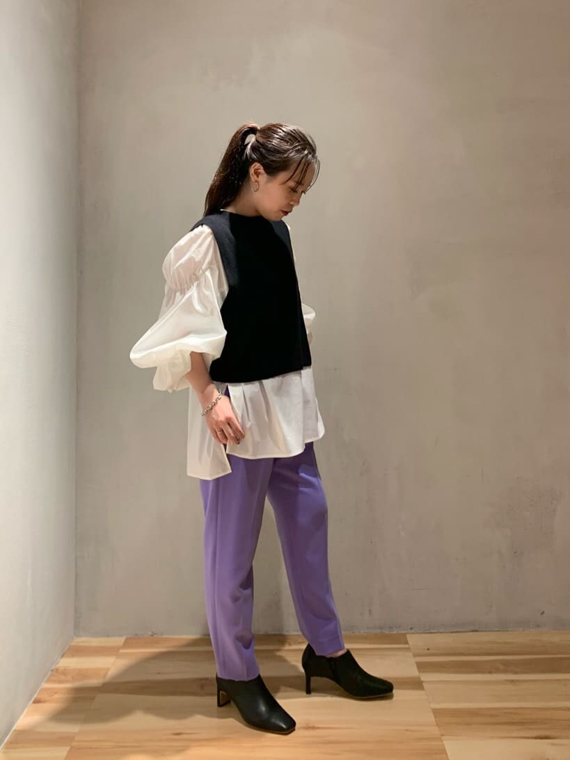 パープル系のスラックス、ホワイト系のニット/セーター、ブラック系のブーツを着用したレディースの秋コーディネートの3枚目の写真