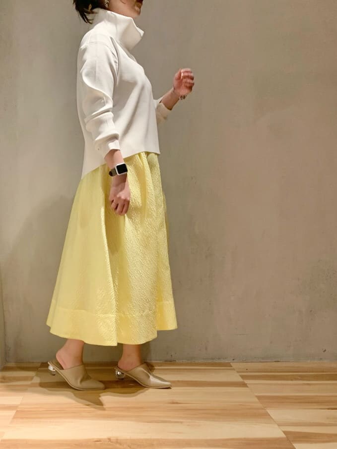 イエロー系のスカート、ホワイト系のニット/セーターを着用したレディースの冬コーディネートの3枚目の写真