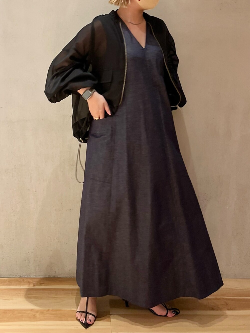 ブラック系のブルゾン、ブルー系のワンピース、ゴールド系のネックレスを着用したレディースの春コーディネートの3枚目の写真