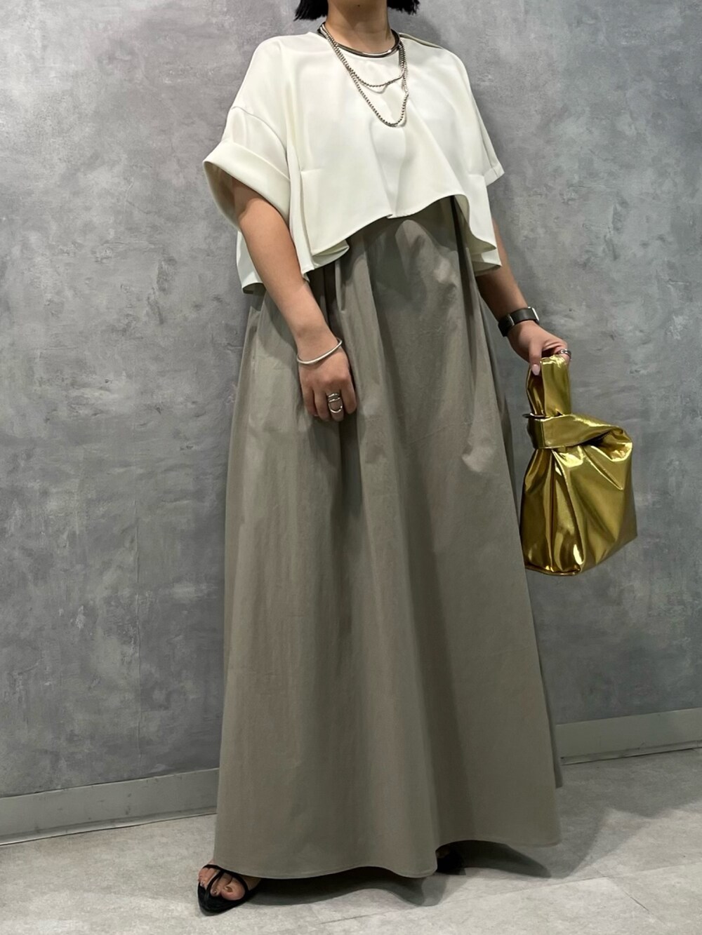 ベージュ系のワンピース、ゴールド系のハンドバッグを着用したレディースの夏コーディネートの3枚目の写真
