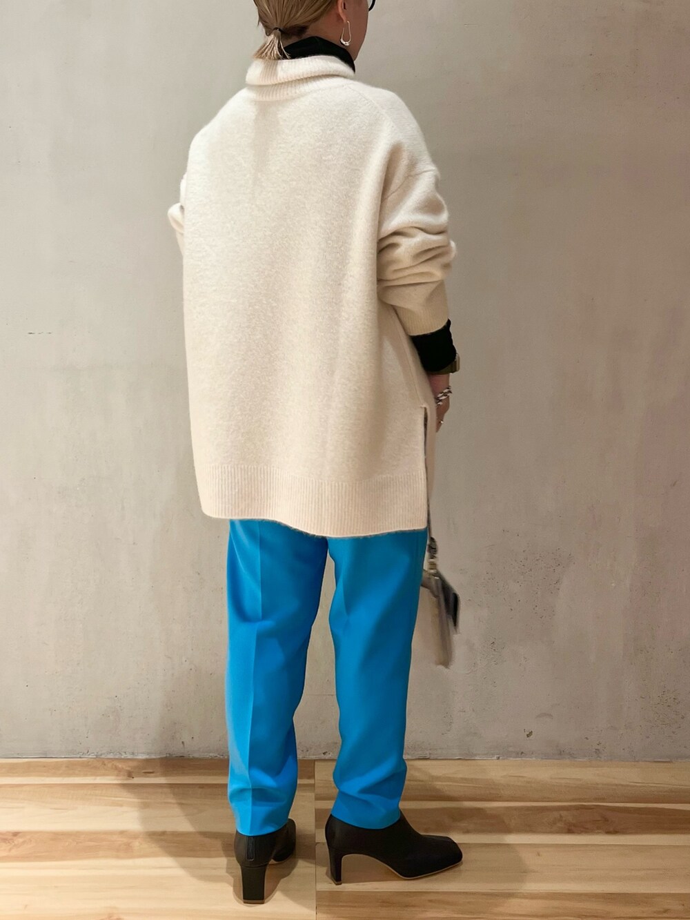 ブラック系のブーツ、ブラック系のTシャツ/カットソー、ホワイト系のニット/セーターを着用したレディースの冬コーディネートの3枚目の写真