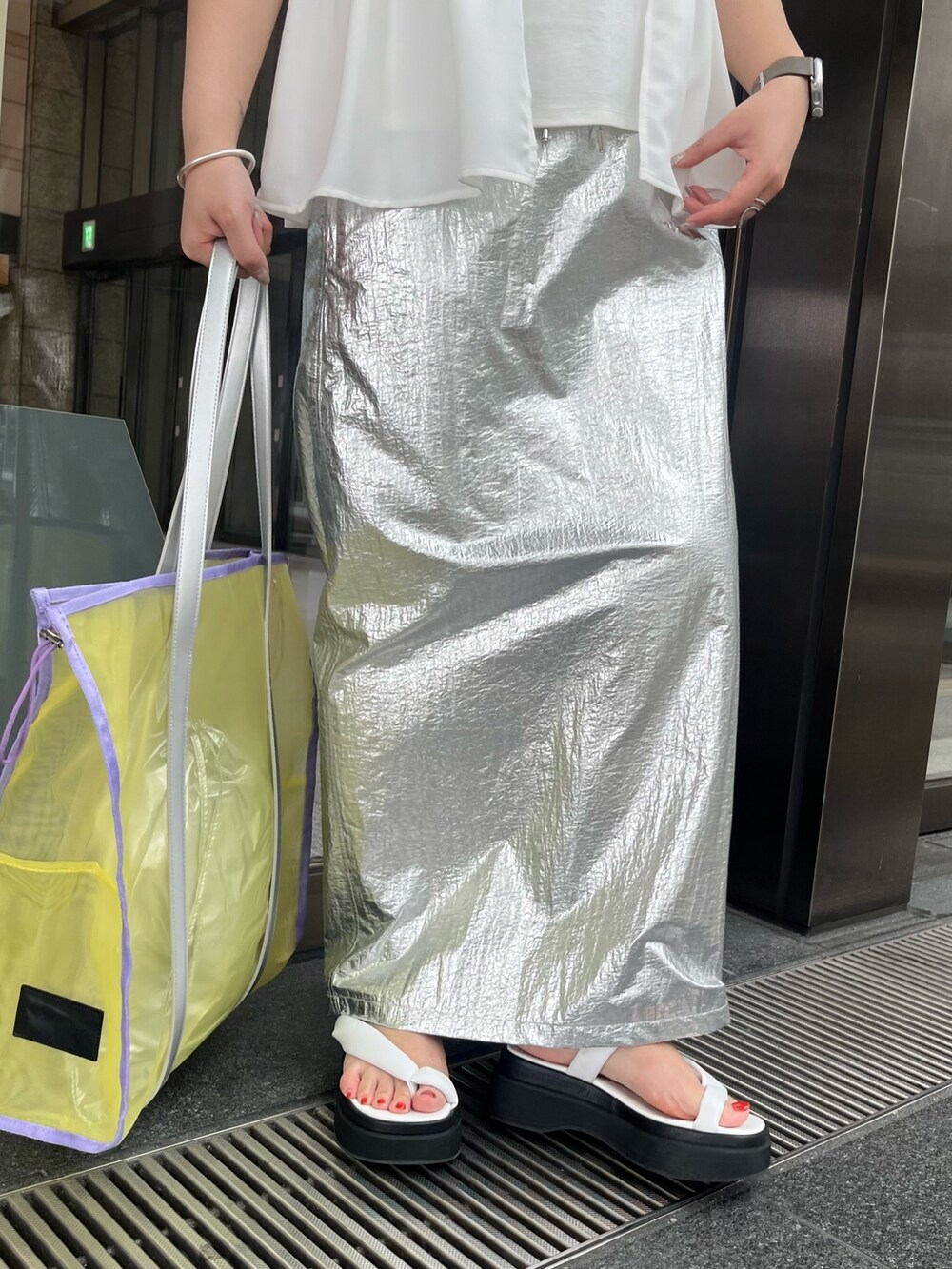 ホワイト系のTシャツ/カットソー、シルバー系のスカート、イエロー系のトートバッグを着用したレディースの春コーディネートの8枚目の写真