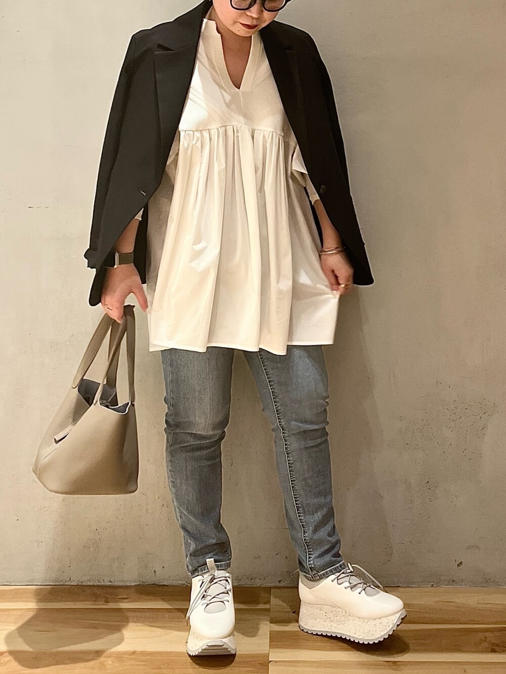 ブラック系のテーラードジャケット、ホワイト系のシャツ/ブラウス、ブルー系のデニムパンツを着用したレディースの冬コーディネートの3枚目の写真