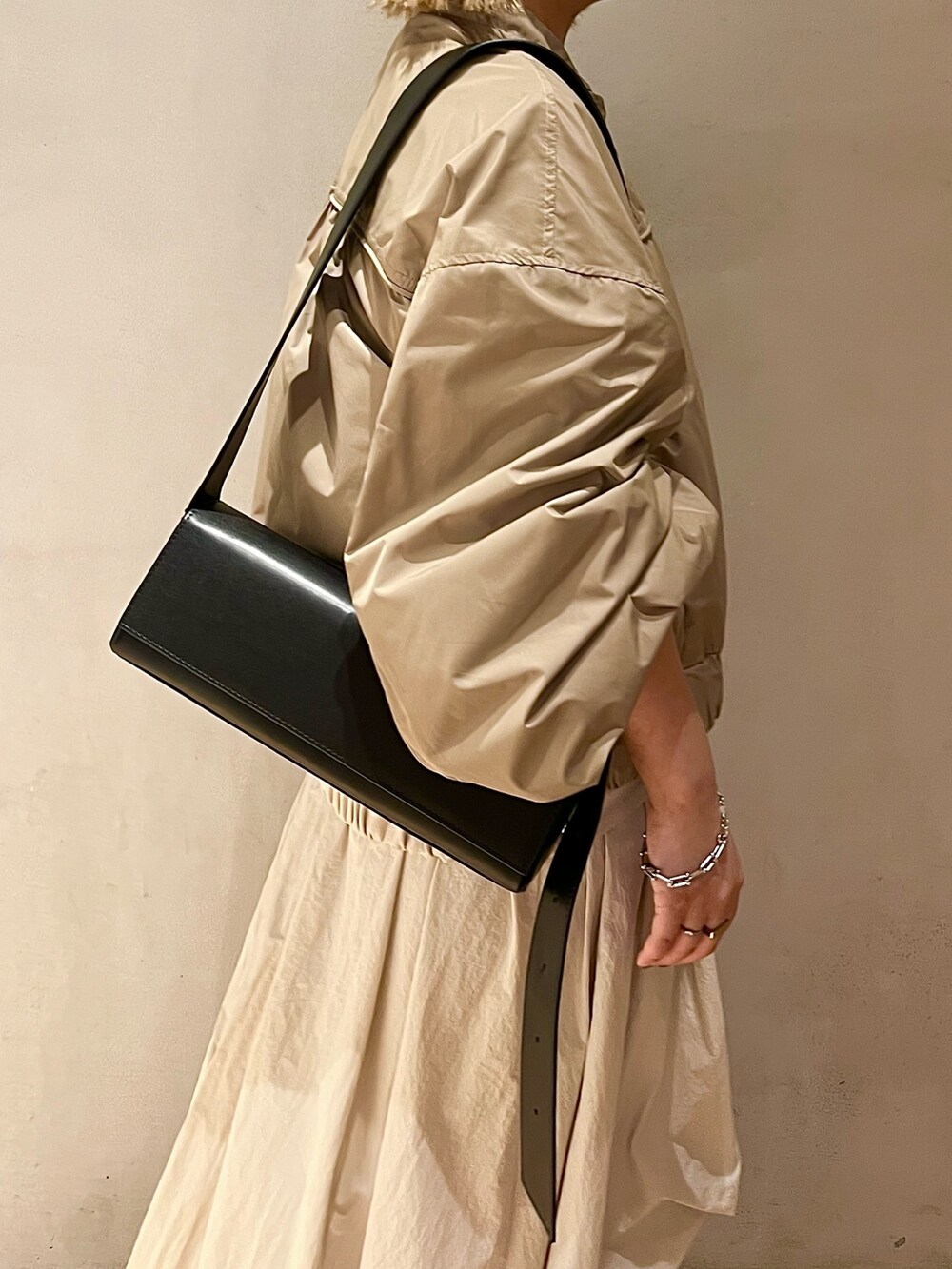 ベージュ系のブルゾン、ベージュ系のワンピース、ブラック系のブーツを着用したレディースの夏コーディネートの6枚目の写真