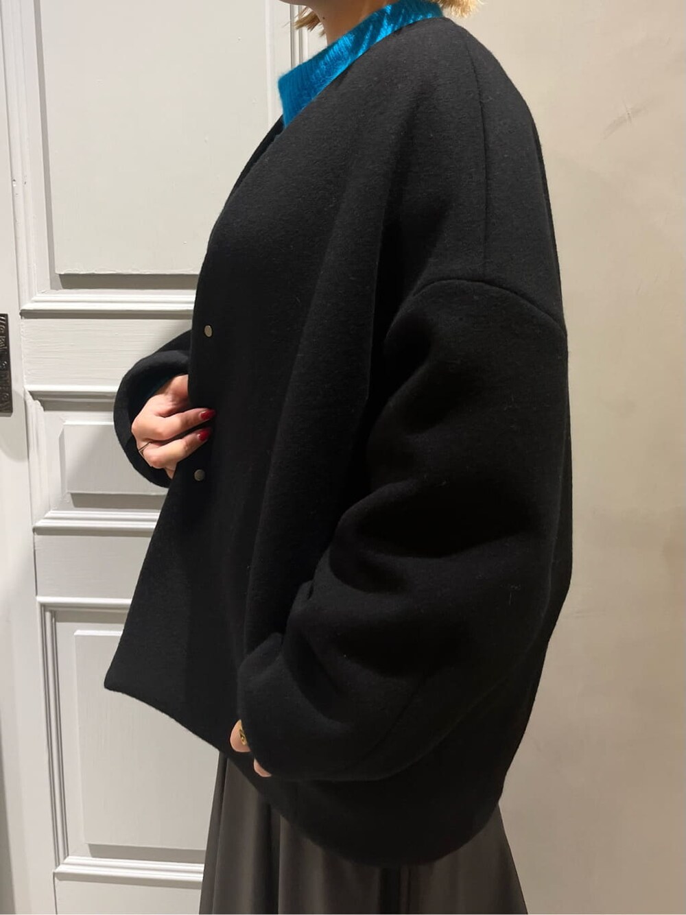 ブラック系のスカート、ブラック系のノーカラーコート、ブルー系のニット/セーターを着用したレディースの秋コーディネートの6枚目の写真