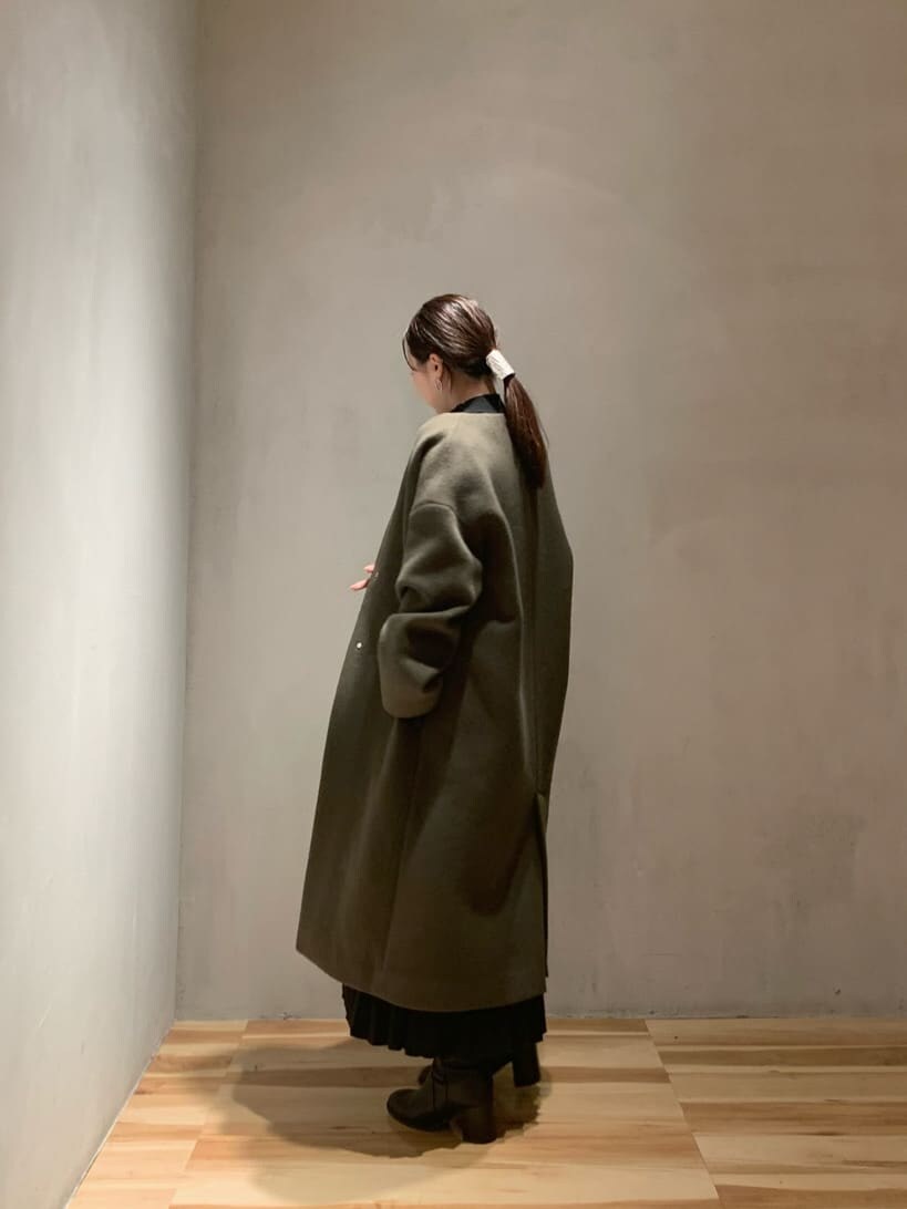 ブラック系のスカート、ブラック系のニット/セーター、ベージュ系のノーカラーコートを着用したレディースの秋コーディネートの3枚目の写真