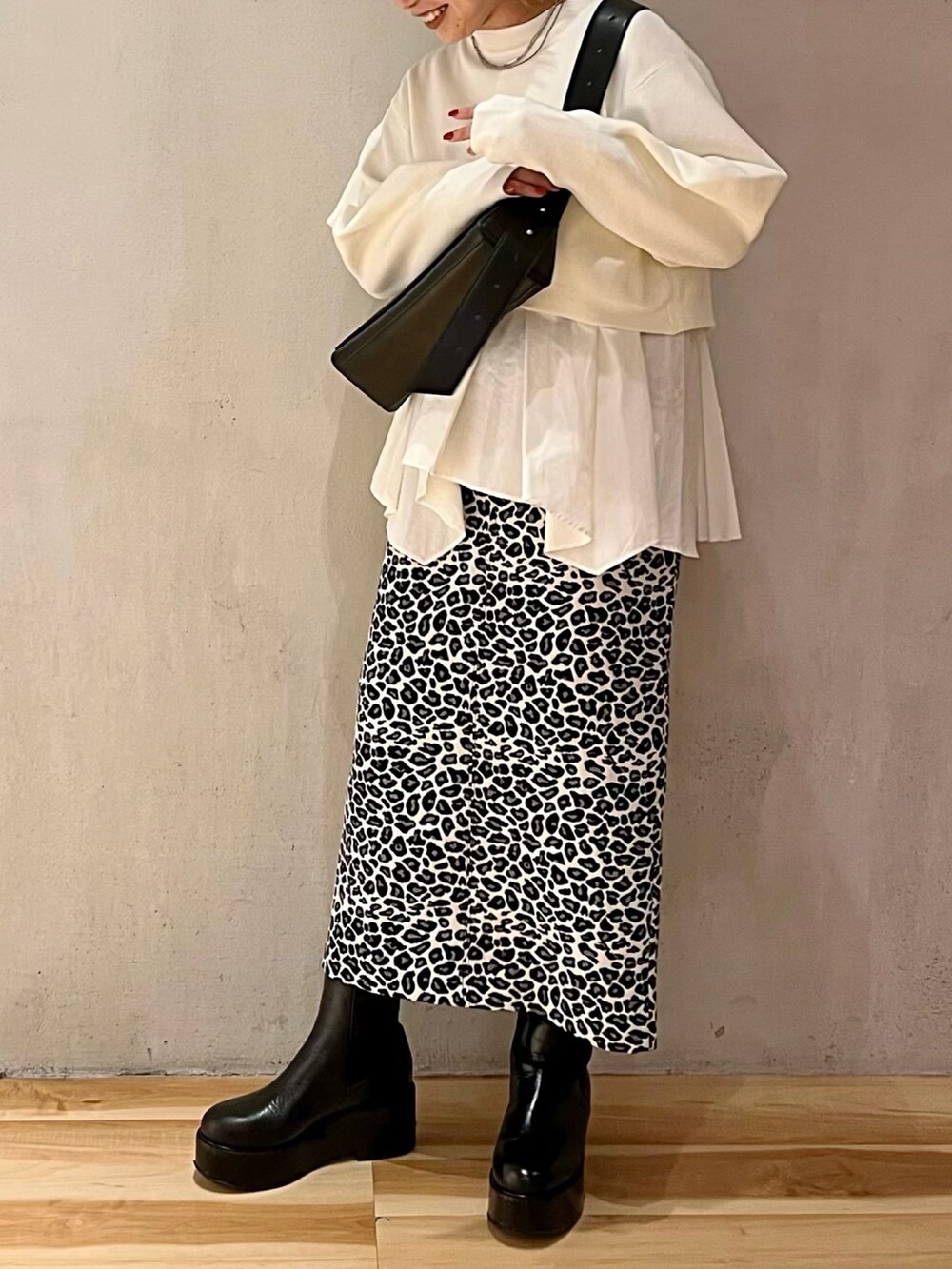 ホワイト系のスカート、ホワイト系のニット/セーター、ブラック系のショルダーバッグを着用したレディースの秋コーディネートの4枚目の写真