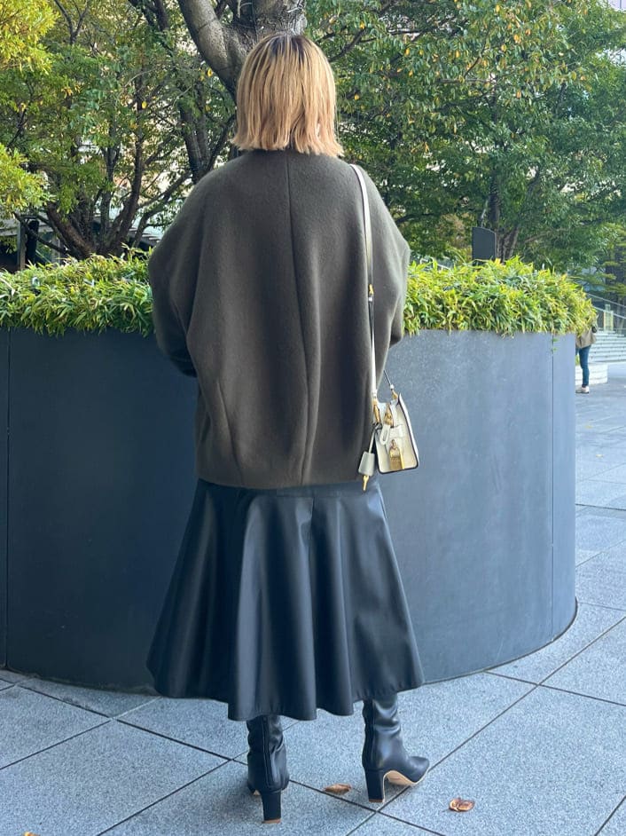 ブラック系のスカート、ブラック系のブーツ、グリーン系のノーカラーコートを着用したレディースの秋コーディネートの3枚目の写真