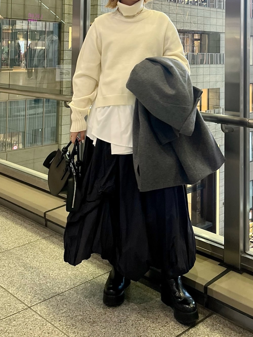 ブラック系のスカート、ブラック系のブーツ、ブラック系のハンドバッグを着用したレディースの冬コーディネートの6枚目の写真