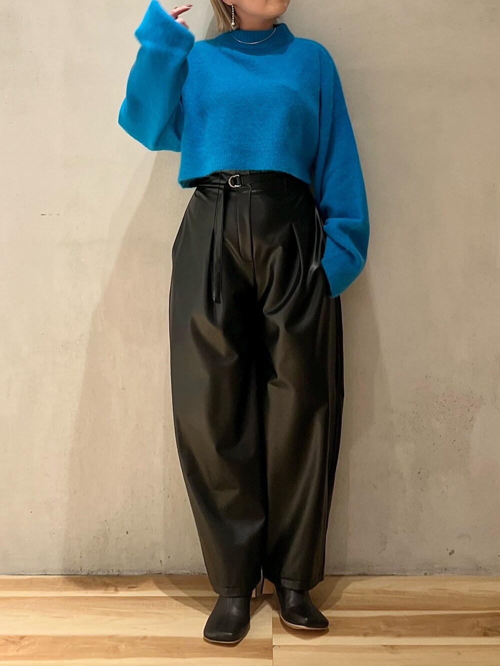 ブルー系のニット/セーター、ブラック系のその他パンツ、ブラック系のブーツを着用したレディースの秋コーディネートの3枚目の写真