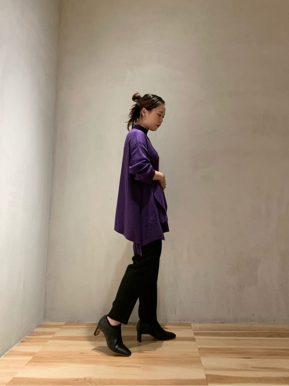 ブラック系のスラックス、ブラック系のブーツ、パープル系のニット/セーターを着用したレディースの秋コーディネートの3枚目の写真