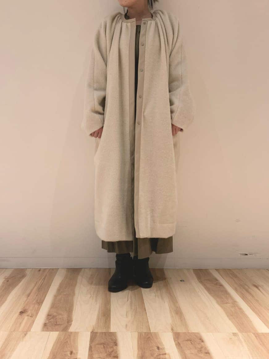 ベージュ系のノーカラーコート、ベージュ系のワンピースを着用したレディースの冬コーディネートの2枚目の写真