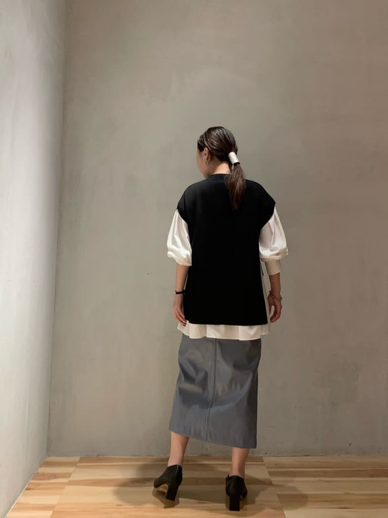 ブラック系のブーツ、ブラック系のニット/セーター、ブルー系のスカートを着用したレディースの秋コーディネートの2枚目の写真