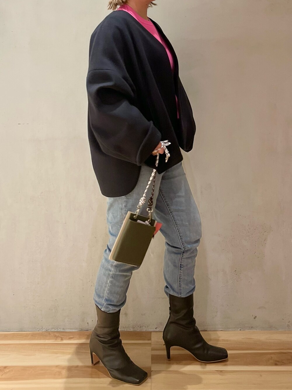 ピンク系のニット/セーター、ブラック系のステンカラーコート、ベージュ系のショルダーバッグを着用したレディースの冬コーディネートの3枚目の写真