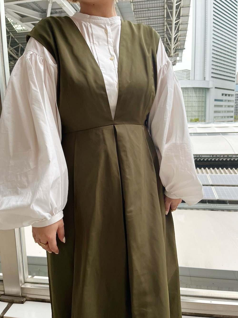 ホワイト系のシャツ/ブラウス、グリーン系のジャンパースカート、ブラック系のブーツを着用したレディースの春コーディネートの5枚目の写真