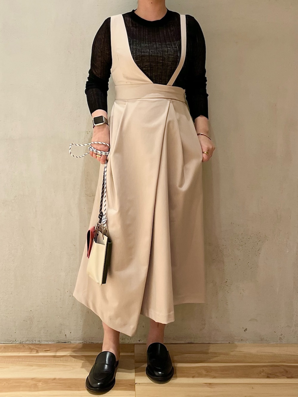 ベージュ系のショルダーバッグ、ベージュ系のジャンパースカート、ブラック系のニット/セーターを着用したレディースの冬コーディネートの4枚目の写真