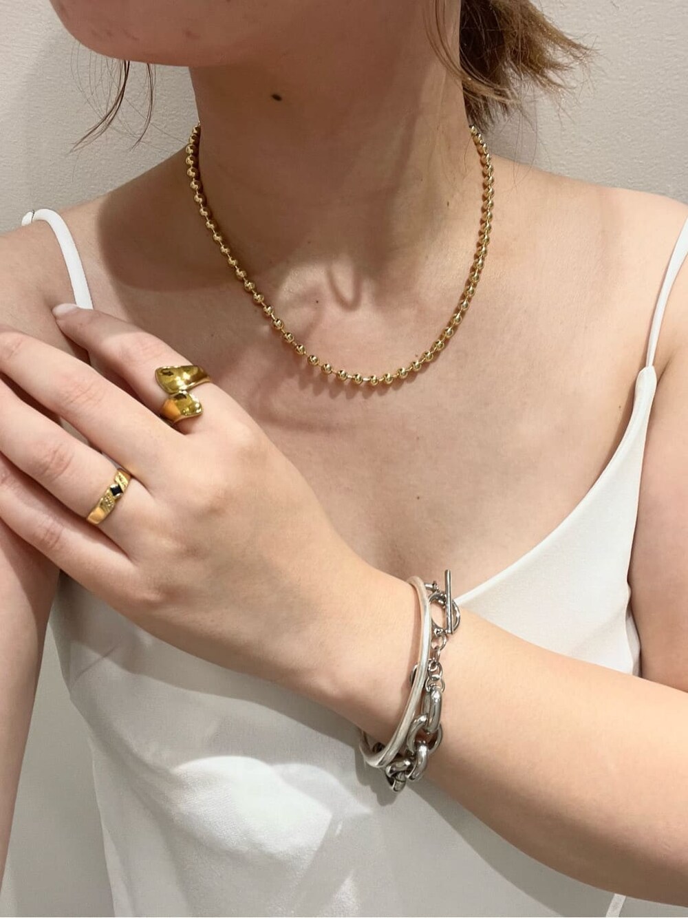 ホワイト系のキャミソール、ゴールド系のネックレスを着用したレディースの夏コーディネートの2枚目の写真