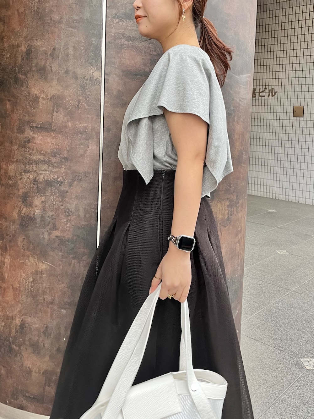 グレー系のTシャツ/カットソー、ブラック系のスカート、ブラック系のパンプスを着用したレディースの春コーディネートの6枚目の写真