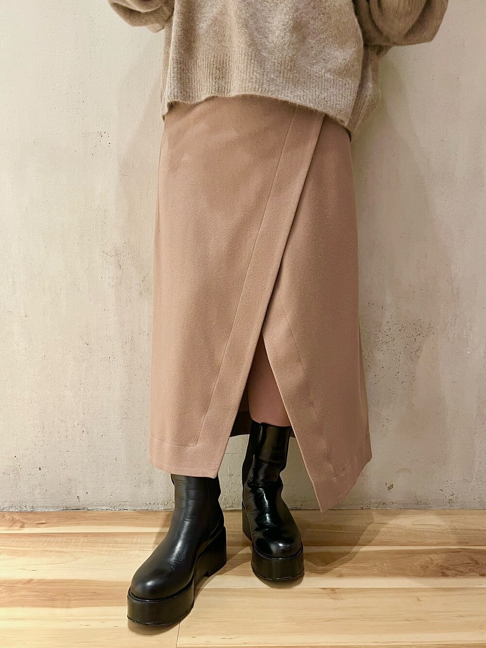 ベージュ系のニット/セーター、ベージュ系のスカート、ブラック系のブーツを着用したレディースの秋コーディネートの7枚目の写真