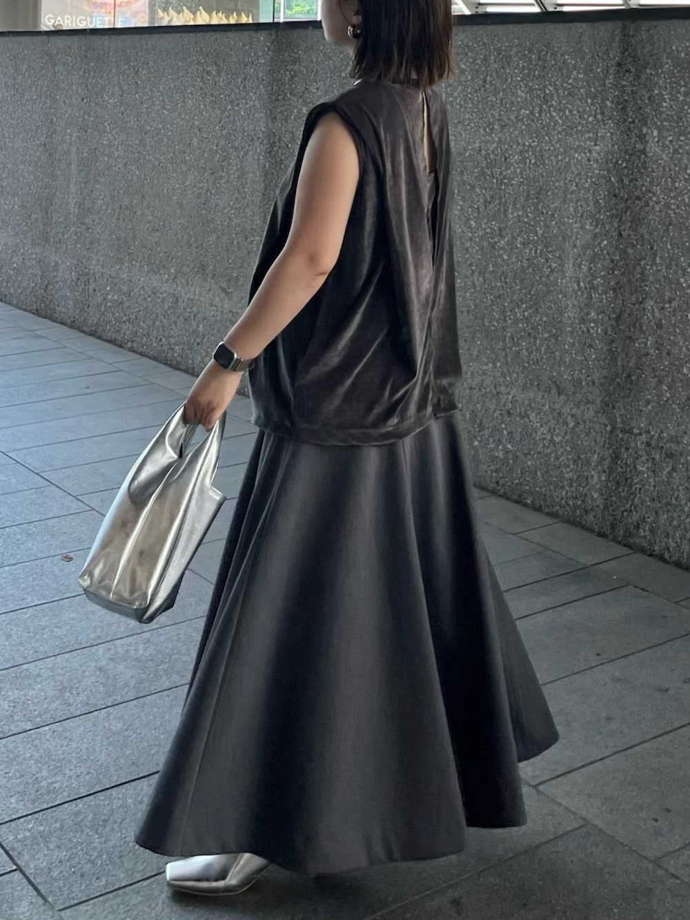 グレー系のスカート、ゴールド系のハンドバッグ、グレー系のTシャツ/カットソーを着用したレディースの夏コーディネートの3枚目の写真