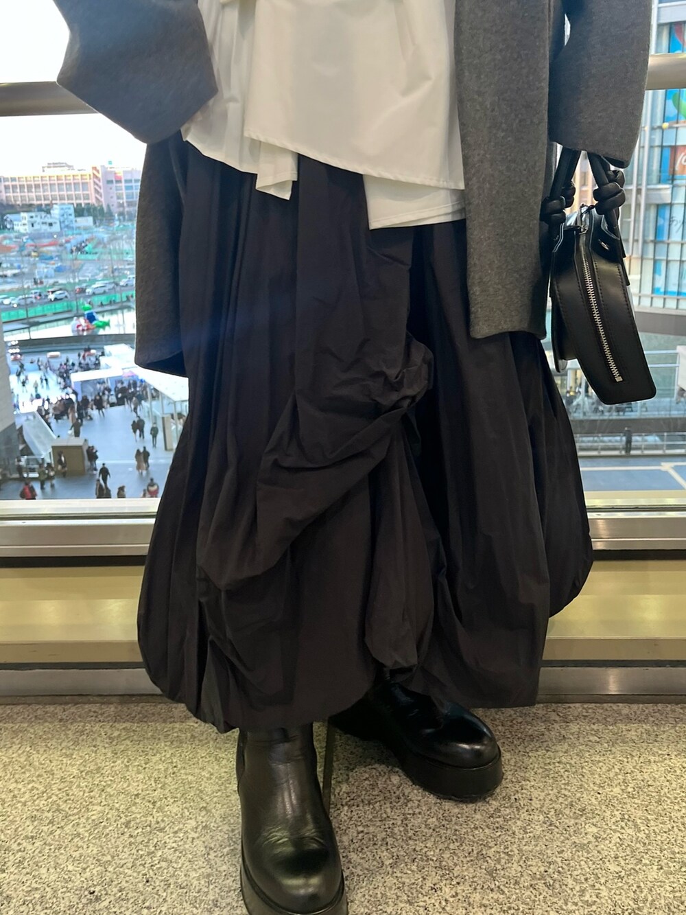 ブラック系のスカート、ブラック系のブーツ、ブラック系のハンドバッグを着用したレディースの冬コーディネートの9枚目の写真