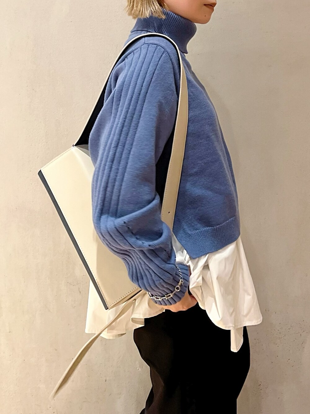 ベージュ系のショルダーバッグ、ブルー系のニット/セーター、ブラック系のブーツを着用したレディースの秋コーディネートの6枚目の写真