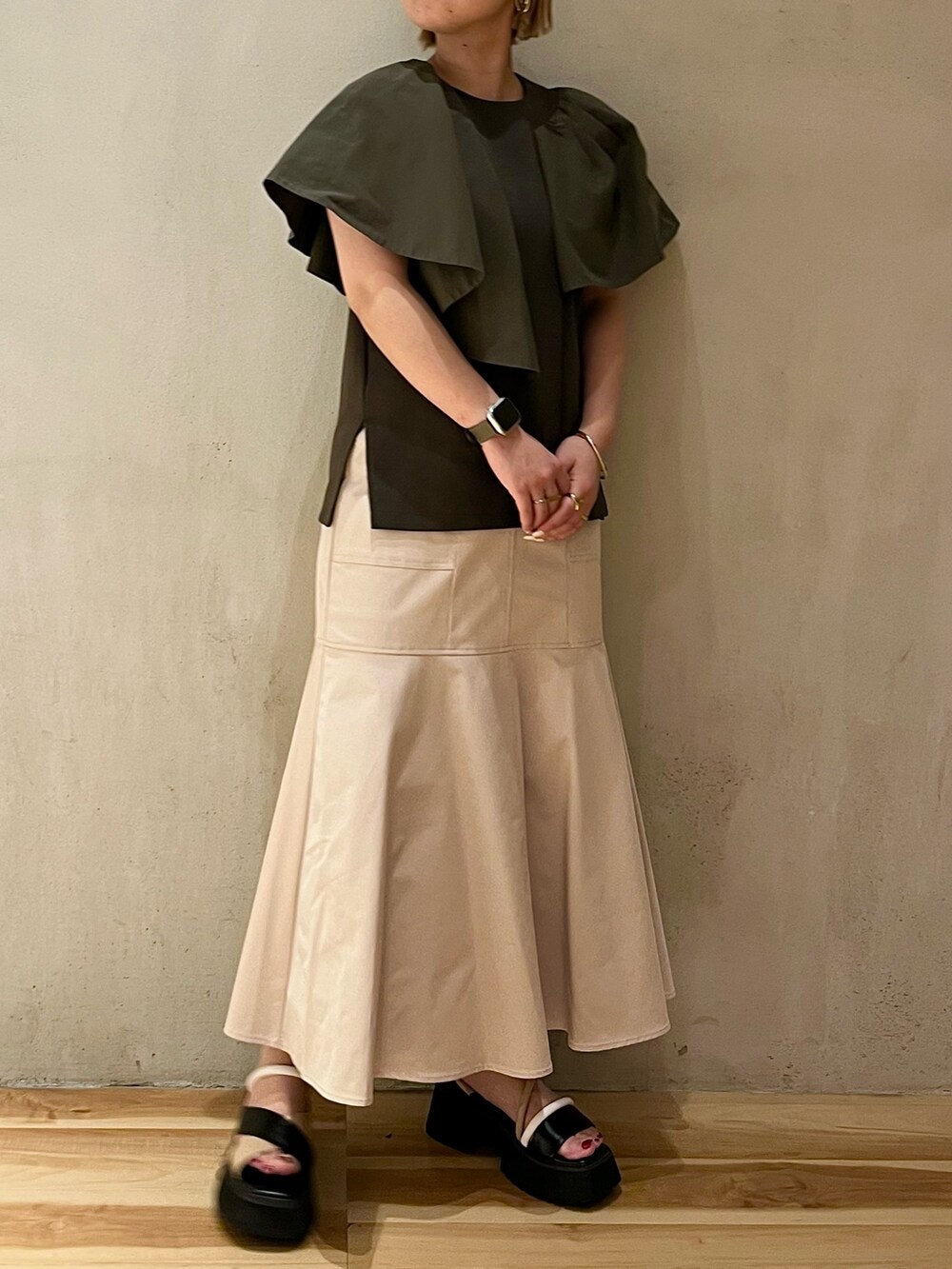 グリーン系のTシャツ/カットソー、ベージュ系のスカート、その他のサンダルを着用したレディースの春コーディネートの4枚目の写真