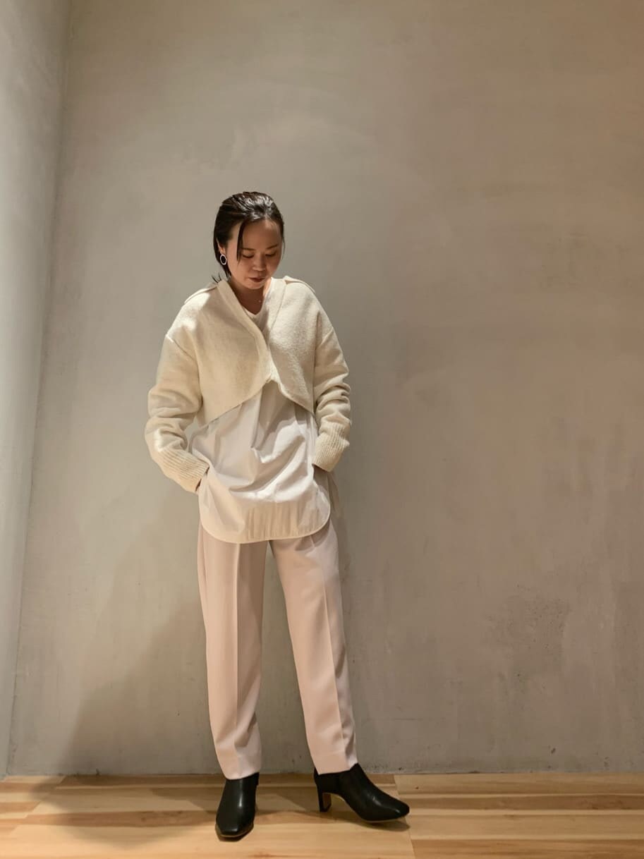 ブラウン系のスラックス、ブラック系のブーツ、ホワイト系のニット/セーターを着用したレディースの秋コーディネートの2枚目の写真