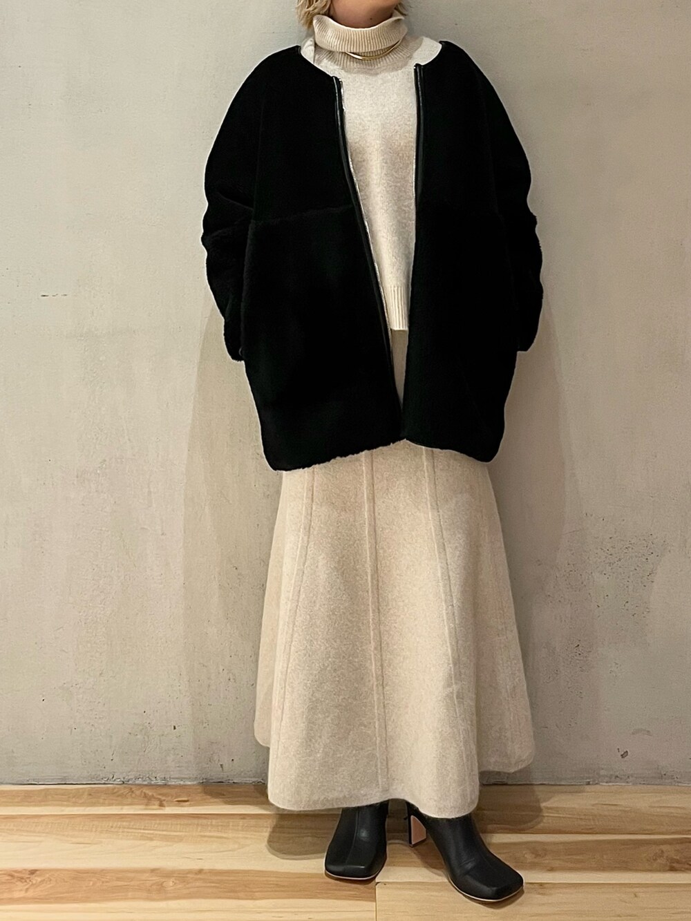 ブラック系のノーカラーコート、ホワイト系のニット/セーター、ホワイト系のスカートを着用したレディースの秋コーディネートの2枚目の写真
