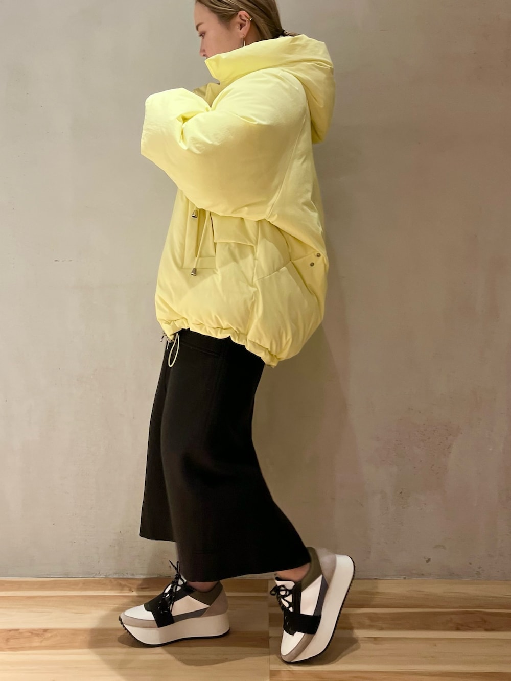 イエロー系のダウンジャケット/コート、グレー系のニット/セーター、ベージュ系のショルダーバッグを着用したレディースの冬コーディネートの2枚目の写真