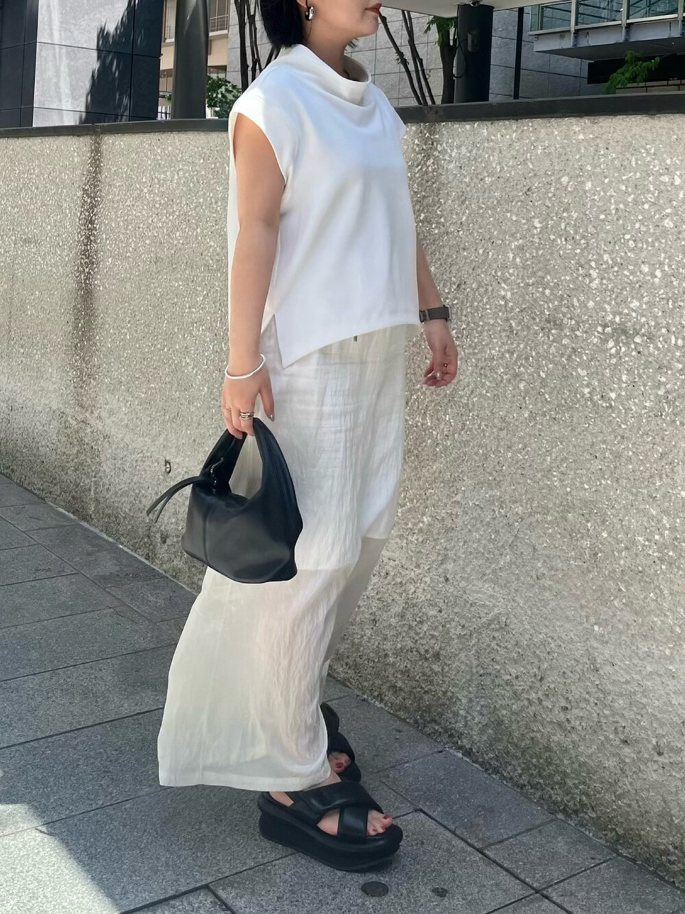 ホワイト系のTシャツ/カットソー、ホワイト系のスカート、ブラック系のサンダルを着用したレディースの春コーディネートの3枚目の写真