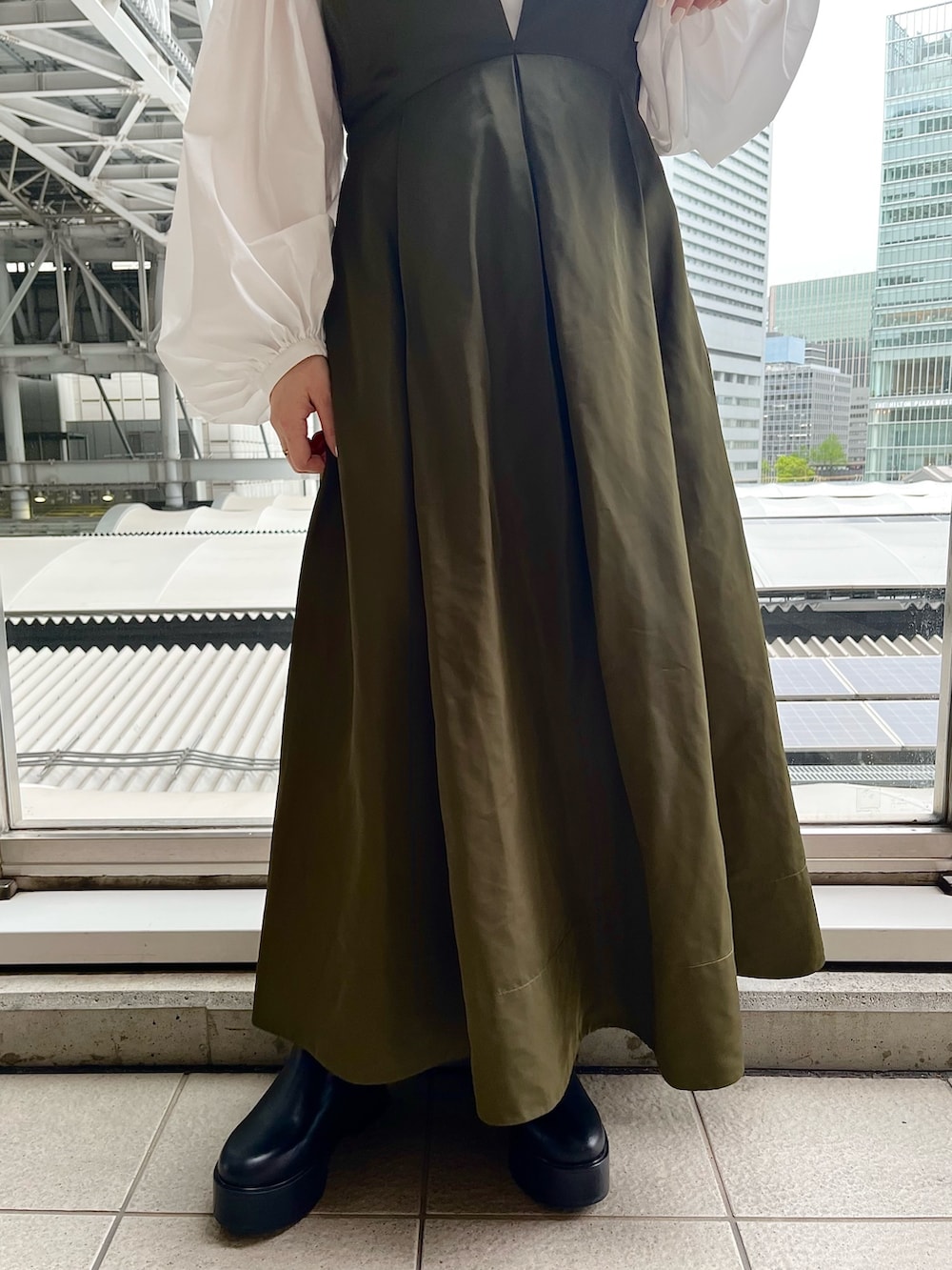 ホワイト系のシャツ/ブラウス、グリーン系のジャンパースカート、ブラック系のブーツを着用したレディースの春コーディネートの7枚目の写真