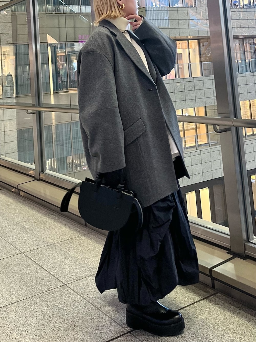 ブラック系のスカート、ブラック系のブーツ、ブラック系のハンドバッグを着用したレディースの冬コーディネートの2枚目の写真