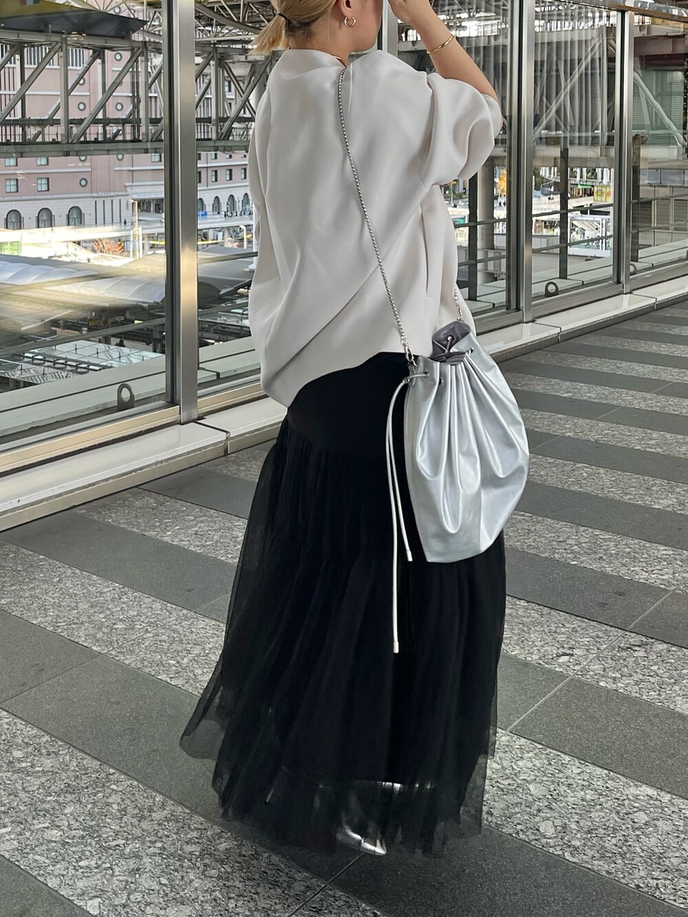 ベージュ系のノーカラーコート、ブラック系のタンクトップ、ブラック系のスカートを着用したレディースの冬コーディネートの3枚目の写真