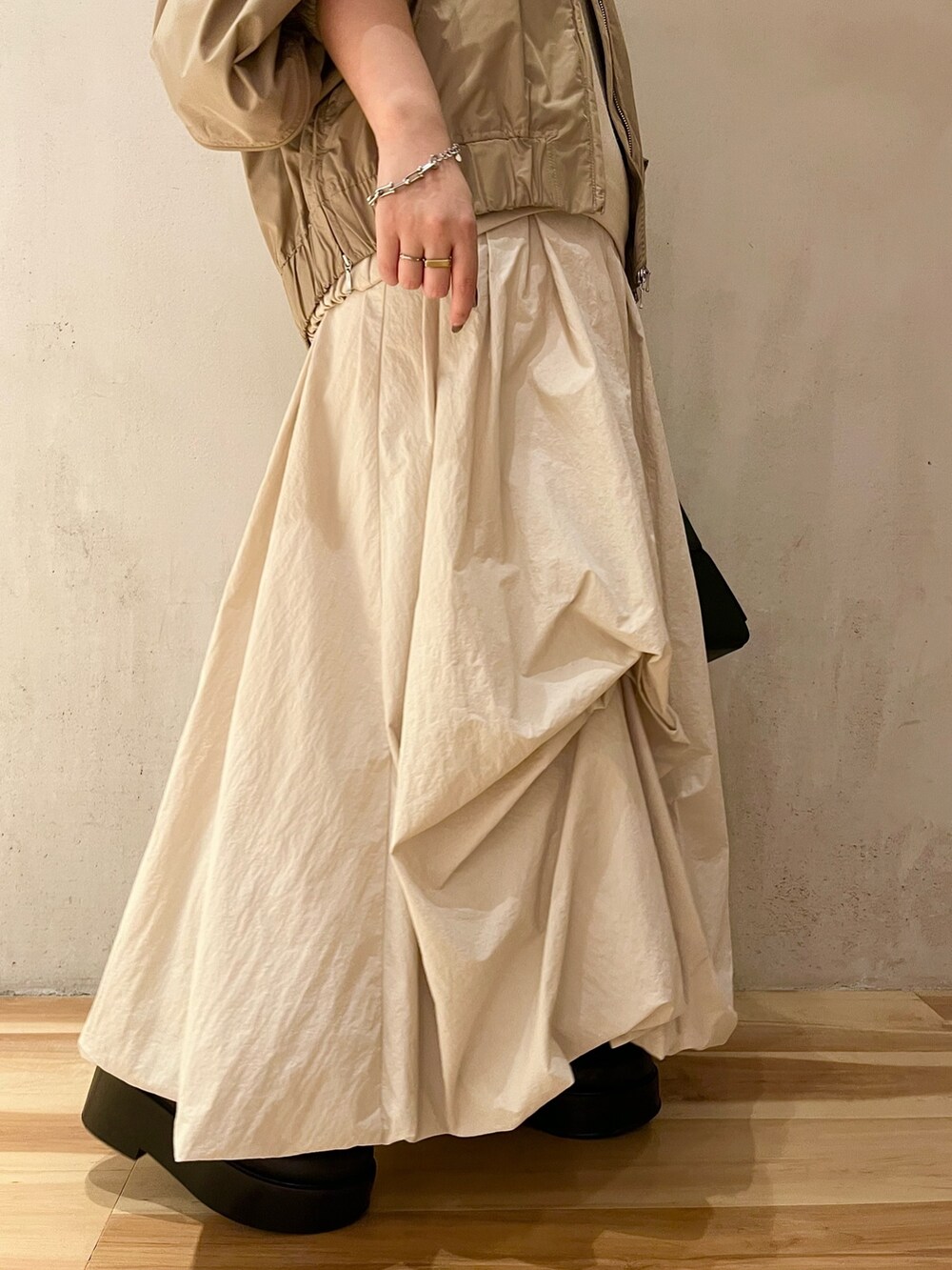 ベージュ系のブルゾン、ベージュ系のワンピース、ブラック系のブーツを着用したレディースの夏コーディネートの7枚目の写真