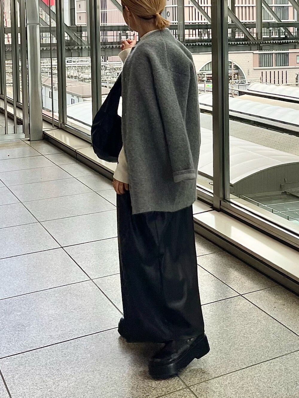 グレー系のノーカラージャケット、ブラック系のジャンパースカート、ホワイト系のニット/セーターを着用したレディースの秋コーディネートの2枚目の写真