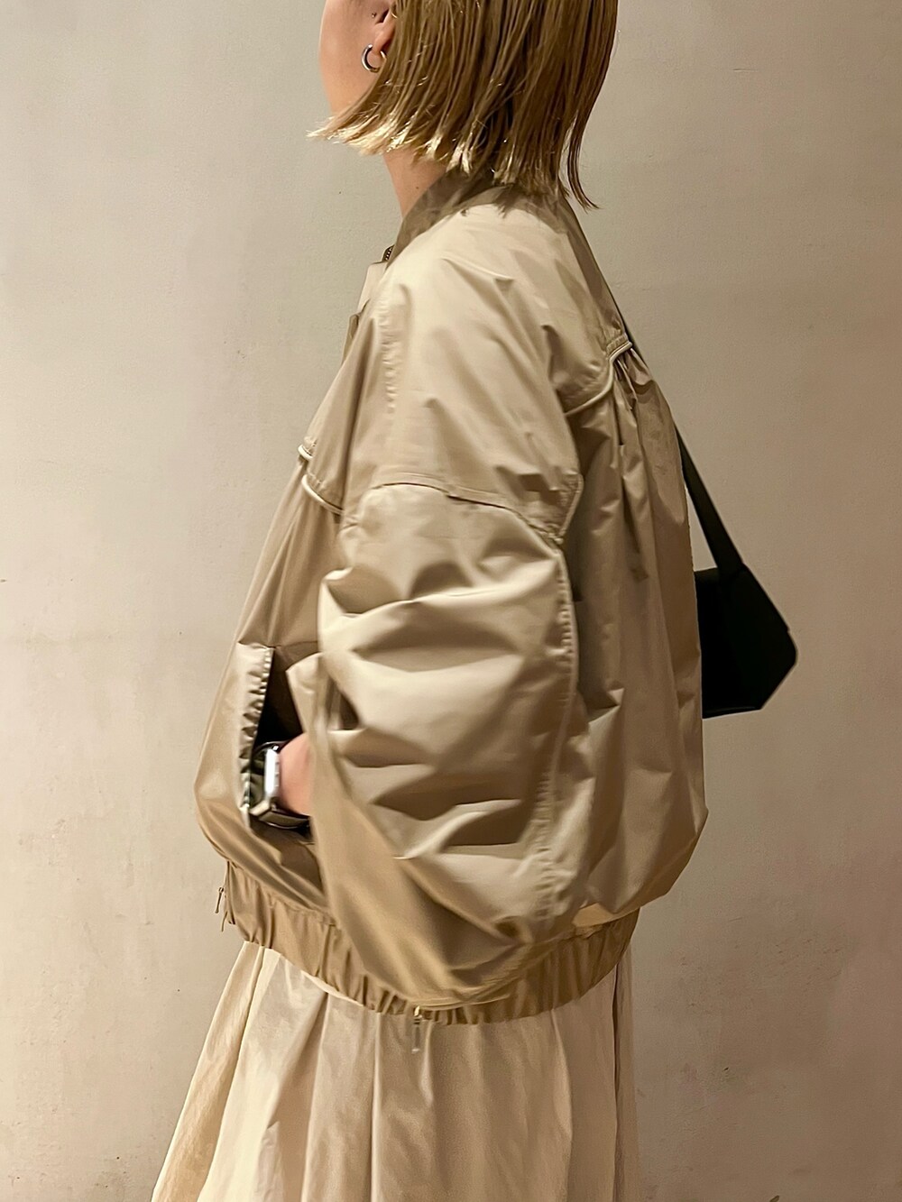 ベージュ系のブルゾン、ベージュ系のワンピース、ブラック系のブーツを着用したレディースの夏コーディネートの5枚目の写真