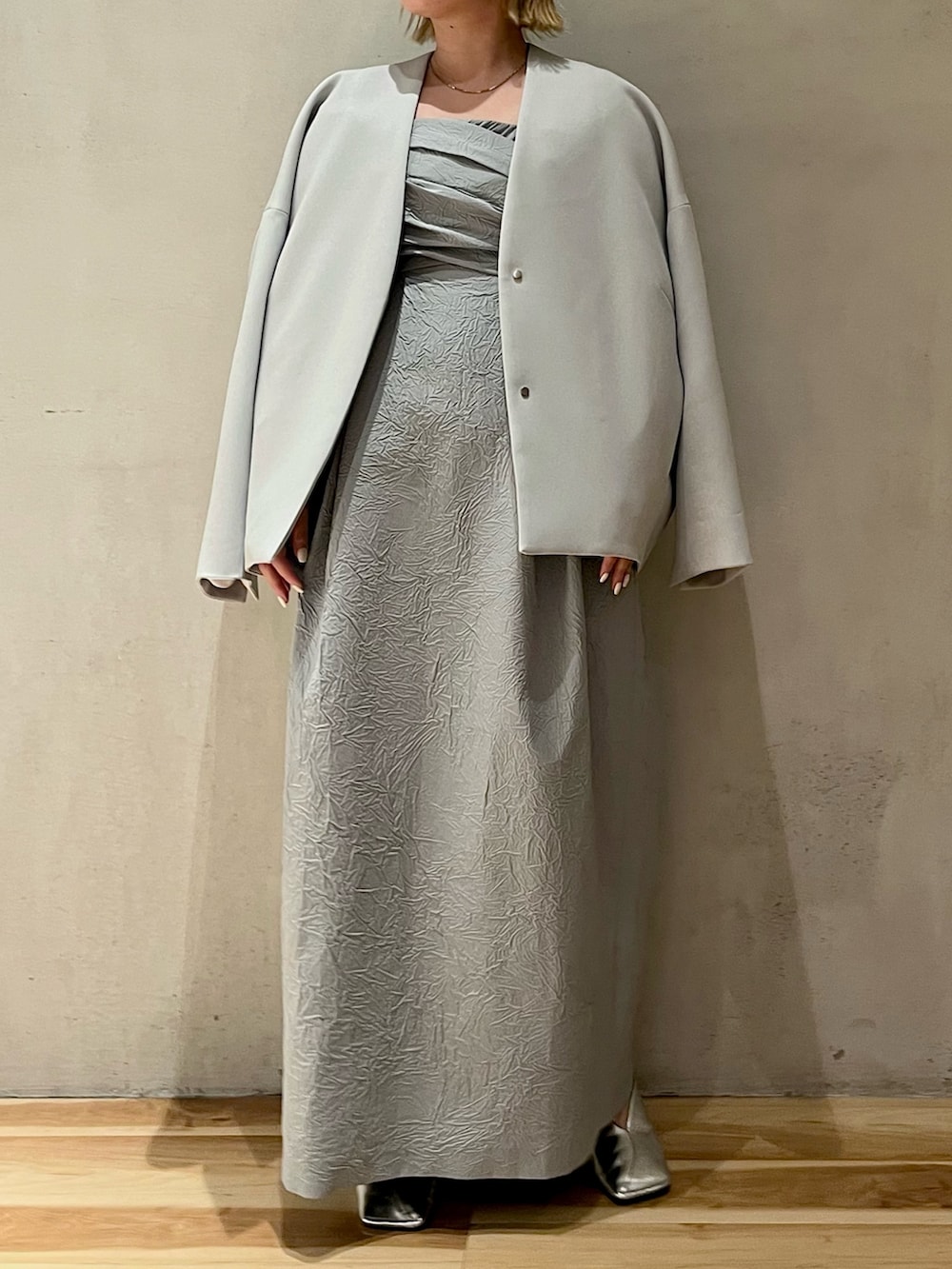 ブルー系のノーカラーコート、シルバー系のパンプス、ブルー系のワンピースを着用したレディースの冬コーディネートの3枚目の写真