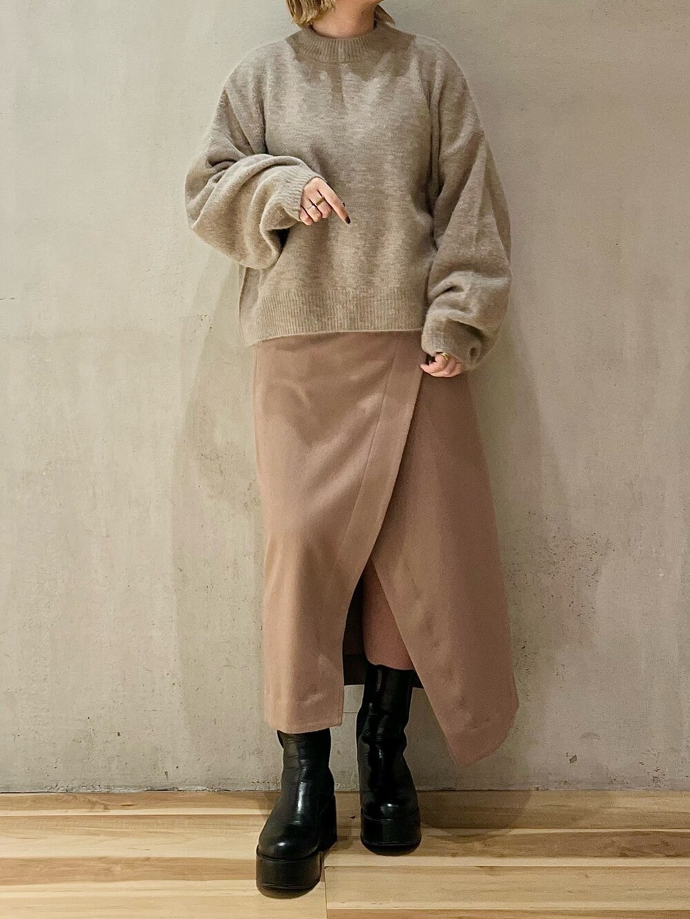 ブラック系のノーカラーコート、ベージュ系のニット/セーター、ベージュ系のスカートを着用したレディースの秋コーディネートの8枚目の写真