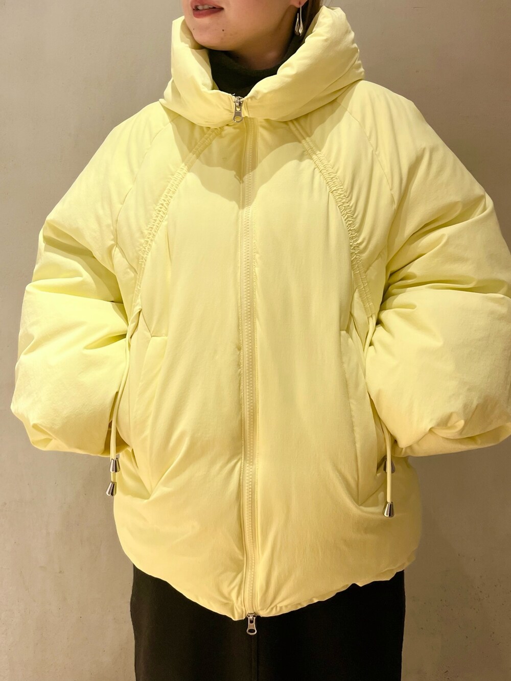 イエロー系のダウンジャケット/コート、グレー系のニット/セーター、ベージュ系のショルダーバッグを着用したレディースの冬コーディネートの6枚目の写真