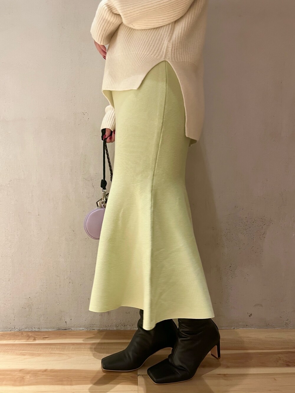 ホワイト系のニット/セーター、ベージュ系のショルダーバッグ、グリーン系のスカートを着用したレディースの冬コーディネートの6枚目の写真