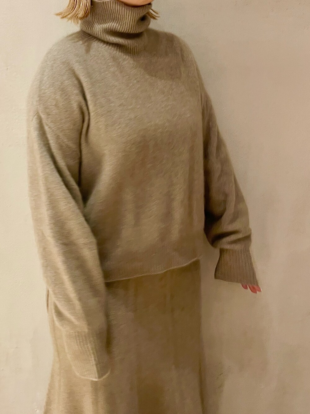 ベージュ系のニット/セーター、ベージュ系のスカート、ブラック系のブーツを着用したレディースの秋コーディネートの5枚目の写真