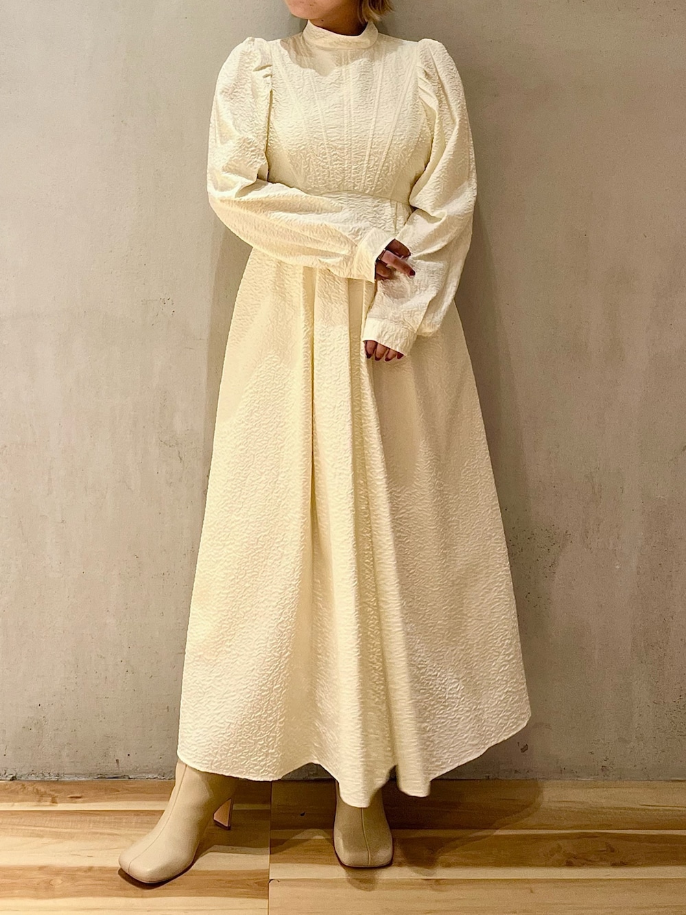 ホワイト系のノーカラージャケット、ホワイト系のワンピース、ベージュ系のブーツを着用したレディースの秋コーディネートの7枚目の写真