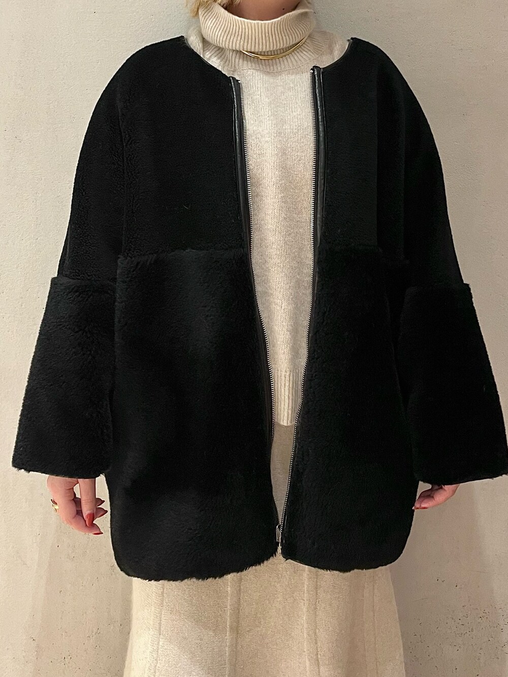 ブラック系のノーカラーコート、ホワイト系のニット/セーター、ホワイト系のスカートを着用したレディースの秋コーディネートの5枚目の写真