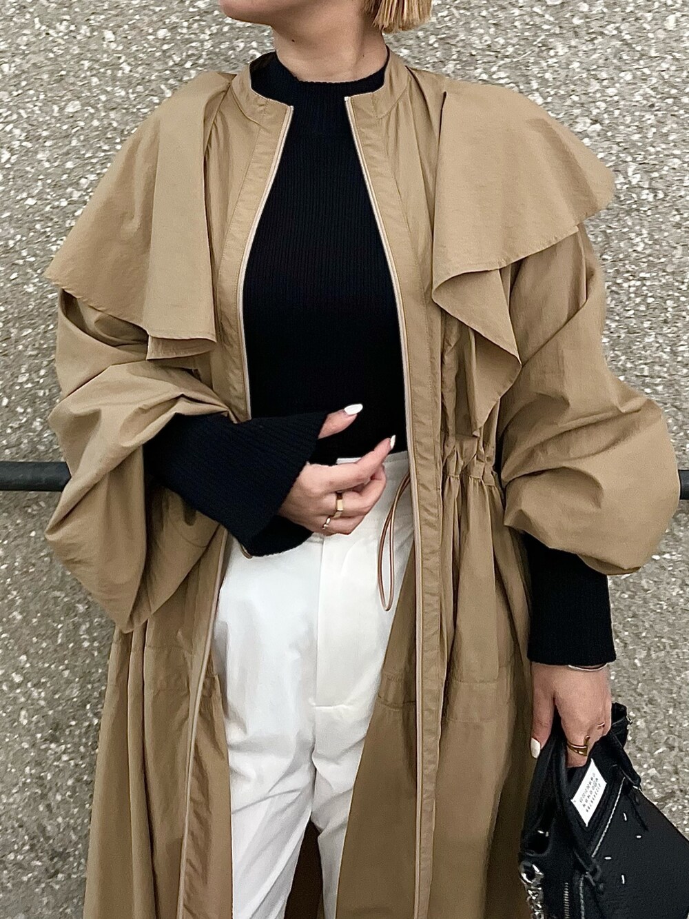 ベージュ系のトレンチコート、ブラック系のニット/セーター、ホワイト系のその他パンツを着用したレディースの春コーディネートの4枚目の写真