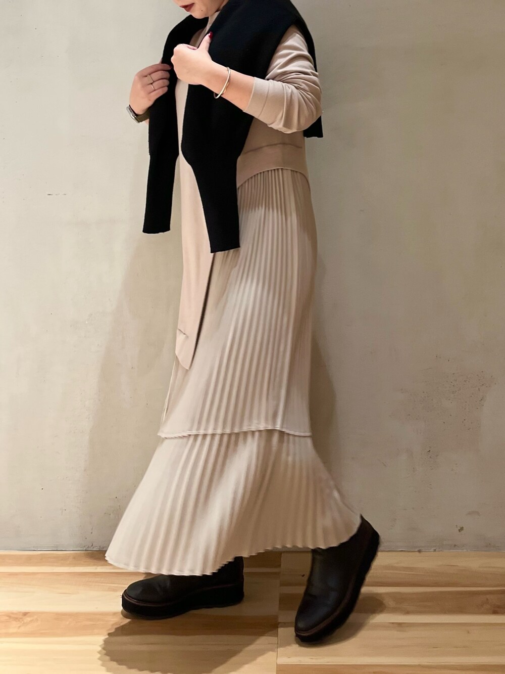 グリーン系のチェスターコート、ブラック系のカーディガン/ボレロ、ベージュ系のワンピースを着用したレディースの冬コーディネートの6枚目の写真